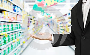 Businessman stretch hand with defocus supermarket aisle background