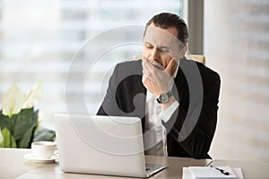 Businessman struggling with drowsiness at work