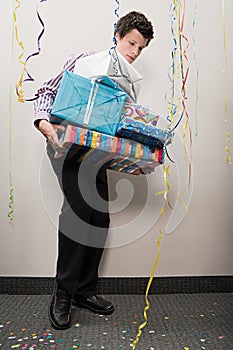 Businessman struggling with pile of presents
