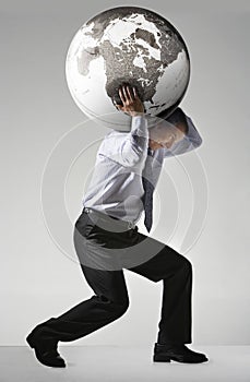 Businessman Struggling To Carry Globe On Shoulders photo