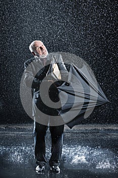 Businessman Struggling To Open Umbrella In Rain