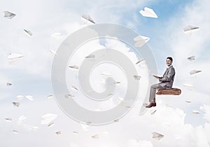 Businessman or student reading book and paper planes flying arou