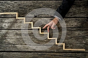 Businessman or student walking his fingers up wooden steps