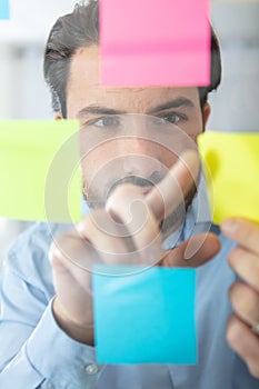 businessman studying reminder notes on window