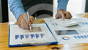 Businessman studying statistics and analyzing pens and graphing documents on a desk with a laptop and a calculator