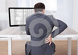 Businessman suffering from backache while sitting at desk