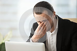 Businessman suffering from eyes fatigue at work