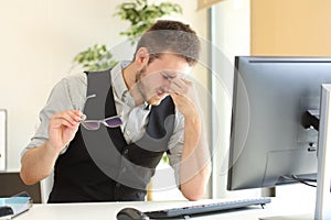 Businessman suffering eyestrain at office photo