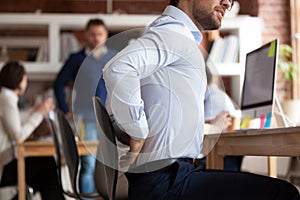 Businessman suffers from lower back pain sitting in shared office