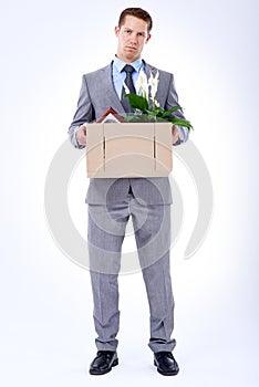 Businessman, suit and box for resignation, fired or transfer at company for liquidation on white backdrop. Employee