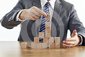 Businessman in a suit building a tower using wooden blocks - marketing strategy concept