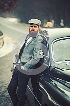 Businessman in suit and cap at retro car. businessman on road.
