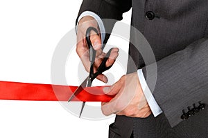 Businessman in suit cutting red ribbon with pair of scissors