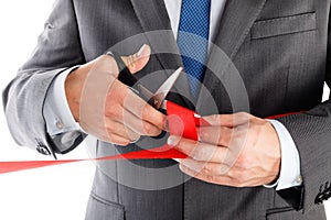 Businessman in suit cutting red ribbon with pair of scissors iso