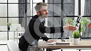 Businessman in a suit enters the office holding out his hand for a handshake.