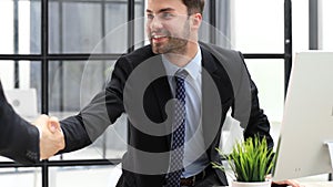 Businessman in a suit enters the office holding out his hand for a handshake.