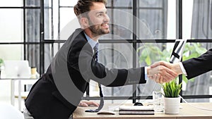 Businessman in a suit enters the office holding out his hand for a handshake.