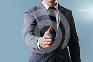 Businessman in suit extending hand, ready for handshake over blue background