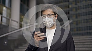Businessman in a suit and face mask to protect himself from new dreadful viruses browsing the Internet using smartphone
