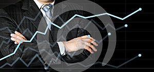 Businessman in a suit with his hands arms crossed looking on graph and think strategy