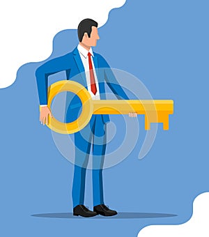 Businessman in suit holding big golden key.