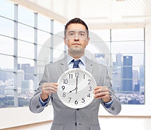 Businessman in suit holding clock with 8 o'clock