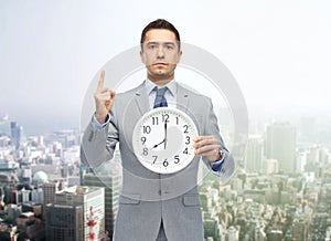 Businessman in suit holding clock with 8 o'clock