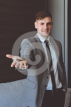 Businessman in suit holding house key in hand. Mortgage, credit or property concept