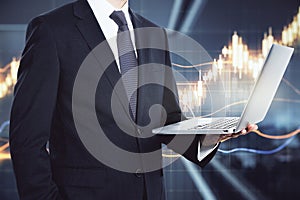 Businessman in a suit holding a laptop with a rising chart in the background closeup. Stock market analysis concept