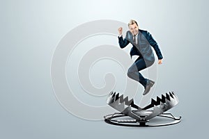 A businessman in a suit jumps into a large metal bear trap. Concept of problem solving, failure, crisis, mixed media