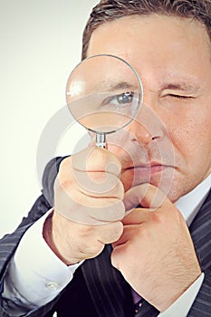 Businessman in a suit looking through a magnifying glass