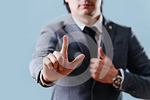Businessman in suit making objection gesture , holding index finger up over blue