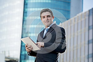 Businessman in suit and necktie holding digital tablet standing outdoors working outdoors business district