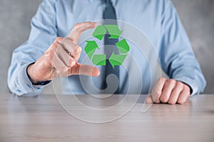 Businessman in suit over dark background holds an recycling icon, sign in his hands. Ecology, environment and conservation concept