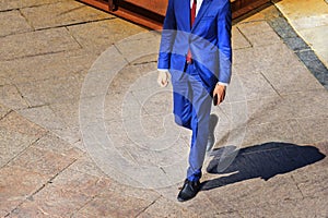 Businessman in a suit with a phone in his hand walks in the square