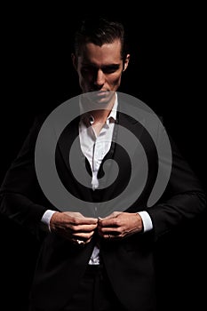 Businessman in suit posing in studio background closing his jack