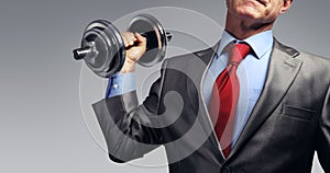 Businessman in suit raising dumbbell. Tax burden concept