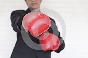 Businessman in suit with red boxing gloves punch to you