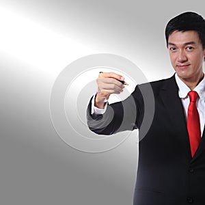 Businessman in a suit with a red tie color holding a pen and writing something.