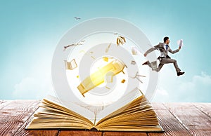 Businessman in suit running on top of a book