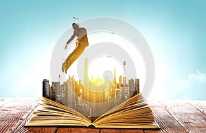 Businessman in suit running on top of a book