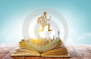 Businessman in suit running on top of a book