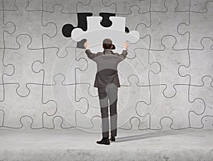 Businessman in suit setting piece of puzzle