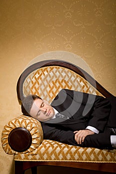 Businessman in suit sleeping on sofa in room