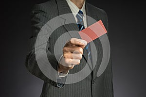 Businessman with suit stretching arm, red business card in hand