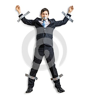 Businessman in suit is taped to the wall with adhesive tape.