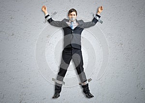 Businessman in suit is taped to the wall with adhesive tape
