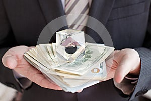 Businessman in suit, tie holds in hands drop of black oil of Brent brand in crystal cube.Pack of hundred dollars bills.Crisis in