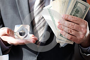 Businessman in suit, tie holds in hands drop of black oil of Brent brand in crystal cube.Pack of hundred dollars bills.Crisis in