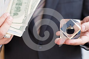 Businessman in suit, tie holds in hands drop of black oil of Brent brand in crystal cube.Pack of hundred dollars bills.Crisis in